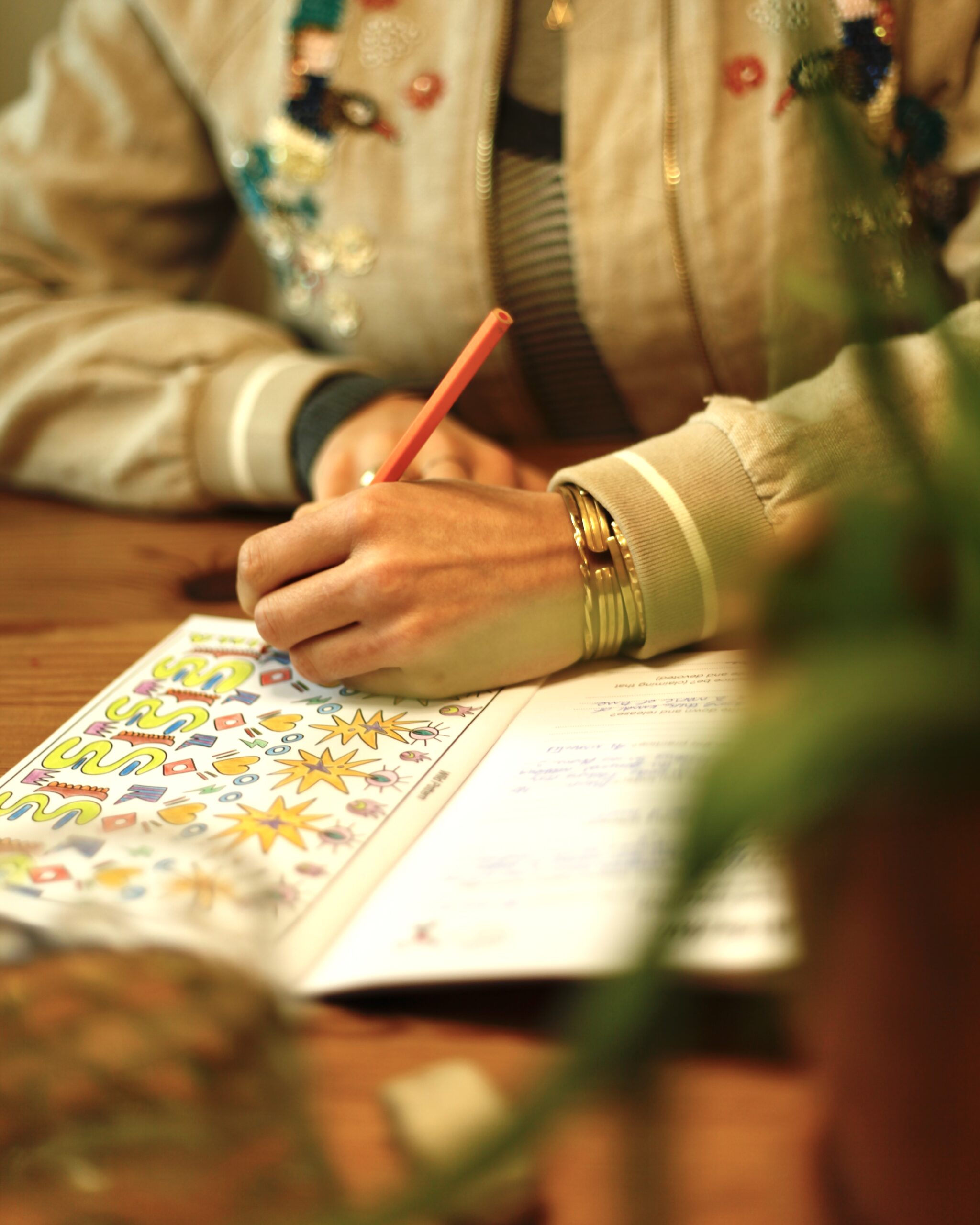 Photo of a hand holding a pencil and colouring in a pattern in a colouring book.